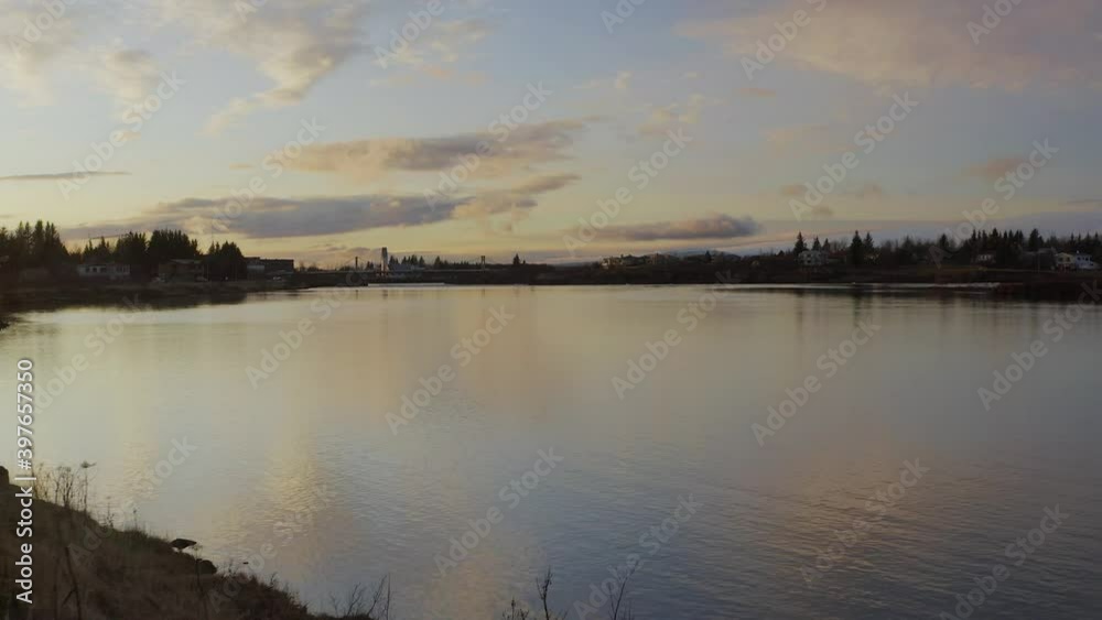 Olfusa River, Olfusarbru Suspension Bridge And Selfoss Town During Golden Hour Of Sunrise In Southern Iceland. - aerial ascend Olfusa River, Olfusarbru Suspension Bridge And Selfoss Town During Golden Hour Of Sunrise In Southern Iceland. - aerial ascend
