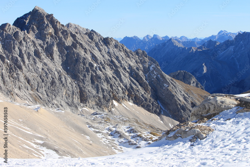 Top of Germany: A large view to the snow coverered and rocky mountain ranges of the Alps from the glacier of the highest german mountain Zugspitze on a beautiful sunny day 