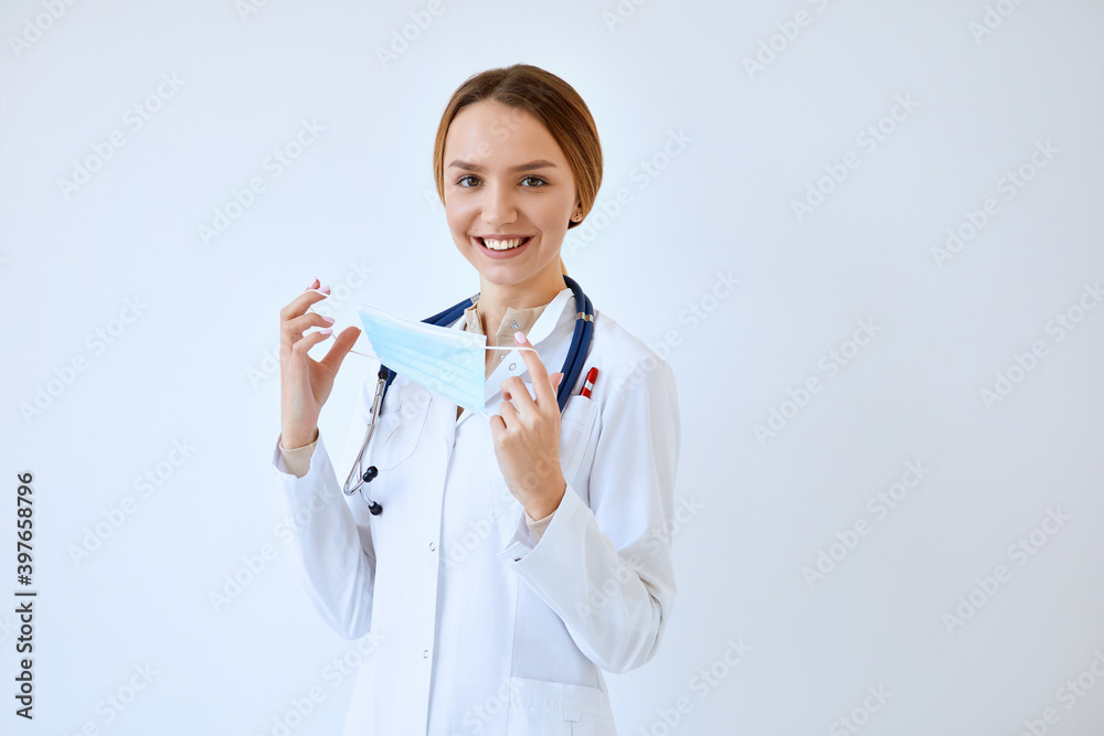 Waist up portrait of beautiful nurse posing confidently while standing with stethoscope and protective face mask against white background Waist up portrait of beautiful nurse posing confidently while standing with stethoscope and protective face mask against white background