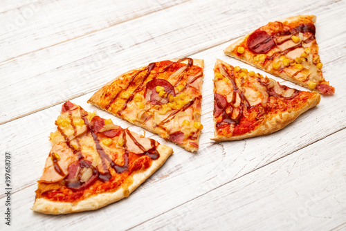 Several slices of pizza on a white wooden background.