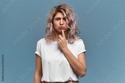 Fototapeta Isolated shot of pretty student girl with messy pinkish hair frowning eyebrows a