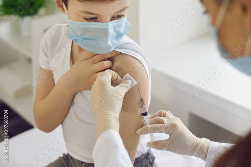 фотографія Boy in face mask getting flu shot at doctor's office during World Immunization W