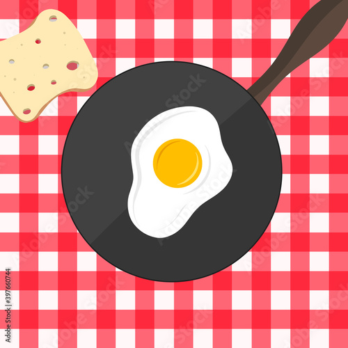 Fried egg and a slice of bread on a red and white tablecloth. Sunny side up and slice of bread. Fried eggs on the pan