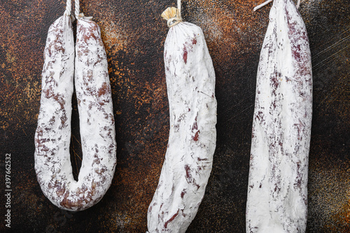 Dry cured chorizo and fuet salami sausages hanging on old metall background