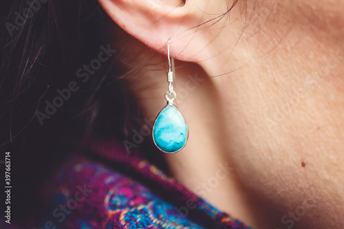 Female ear wearing elegant silver turqoise gemstone earring photo