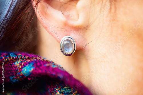 Female ear wearing elegant silver labradorite gemstone earring photo