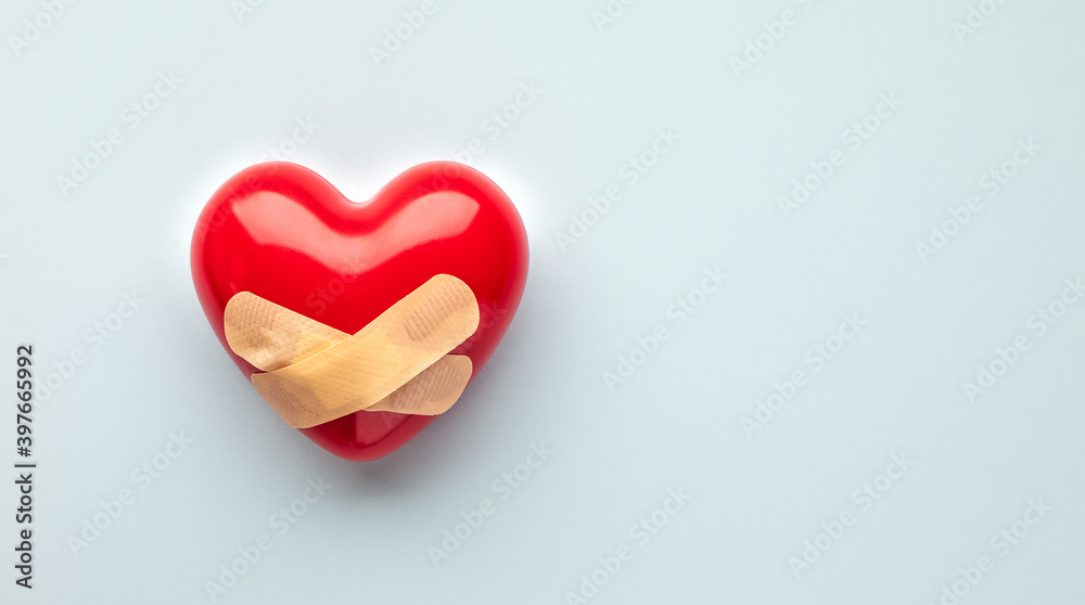 Fototapeta premium Red heart with medical plasters on light blue background, top view, copy space. Concept of renovation or protection of heart