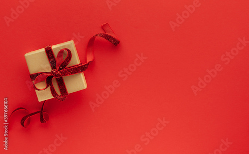 Festive concept with gift box on red background. Top view, copy space.