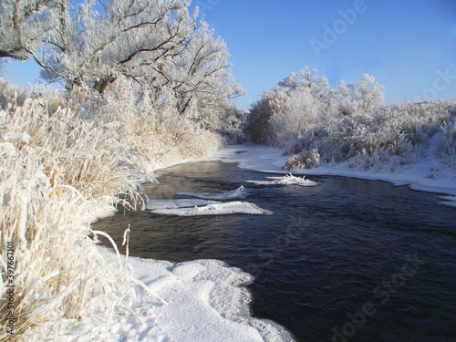 Winter snowy landscape with frosen river at sunny day 