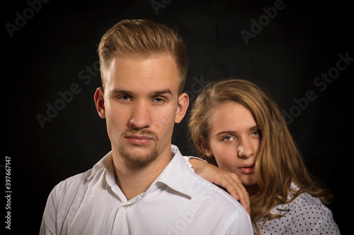 Young beautiful couple studio portrait on black background.