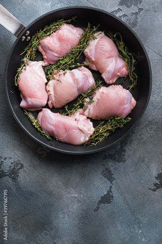 Uncooked chicken thighs  with thime on grill pan on grey backgroundtop viewwith space for text photo