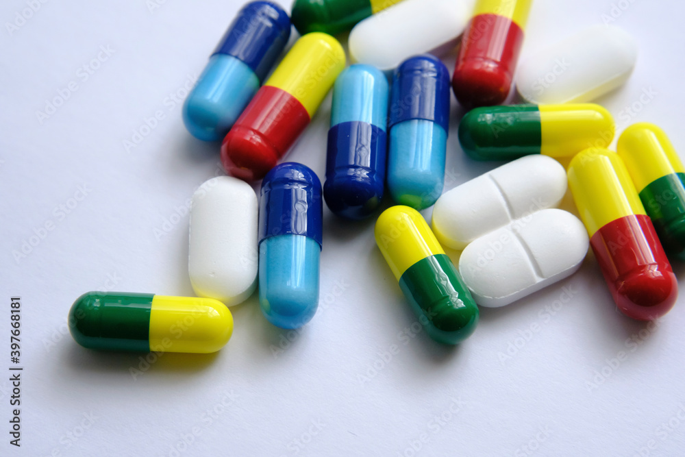 Pile of pills of different colours: blue, yellow, red and white) placed on top of white paper. Illustrative for medical, health and other subjects. Macro. Pile of pills of different colours: blue, yellow, red and white) placed on top of white paper. Illustrative for medical, health and other subjects. Macro.