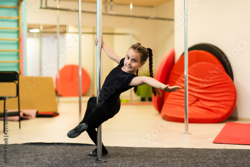Junior acrobat on pylon in the gym