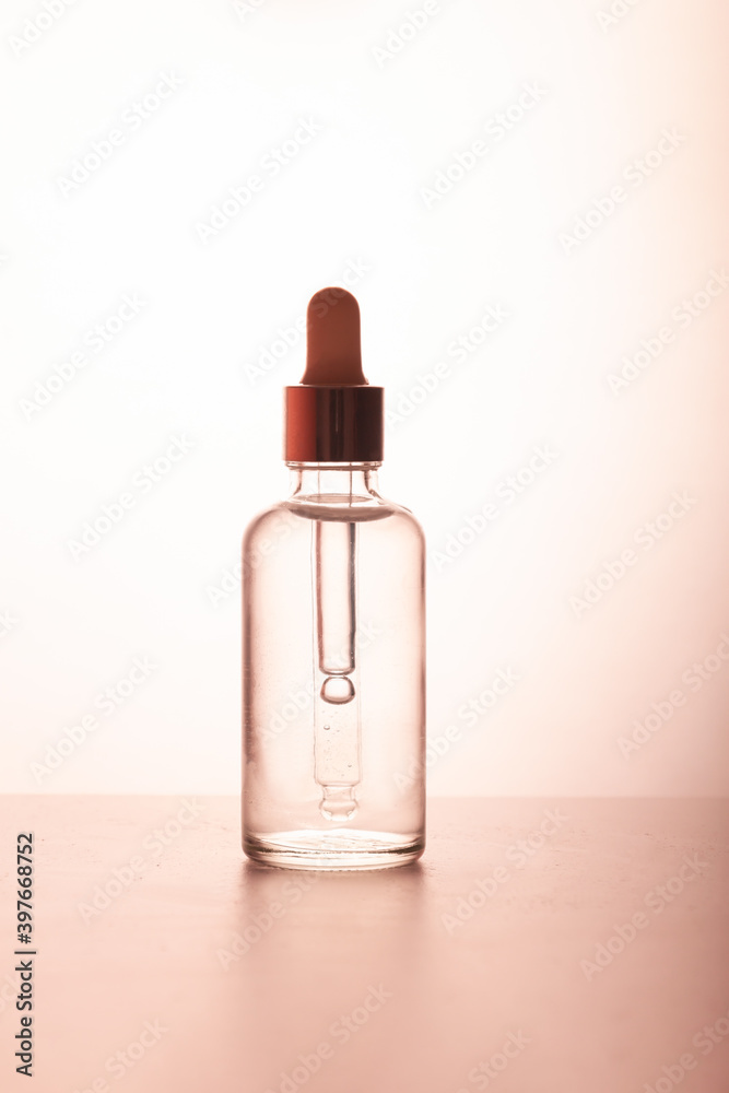 A medical dropper with liquid and a drop falling over a bottle of essence, serum or care oil in the bathroom against a palm tree. The concept of face and body skin care, aromatherapy A medical dropper with liquid and a drop falling over a bottle of essence, serum or care oil in the bathroom against a palm tree. The concept of face and body skin care, aromatherapy