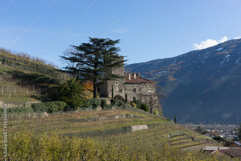 Picturesque mountain landscape in Naturns in South Tyrol in autumn, view from the hill to an old castle and the roofs of old buildings in a vineyard Picturesque mountain landscape in Naturns in South Tyrol in autumn, view from the hill to an old castle and the roofs of old buildings in a vineyard