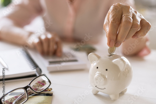 Hands of old women's put money coins in a piggy Bank, the concept of retirement.