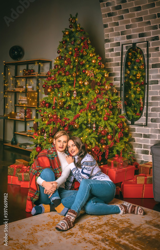 Two pretty women close up under the festive fir-tree indoors with the boxes of gifts.Christmas photo © volhavasilevich