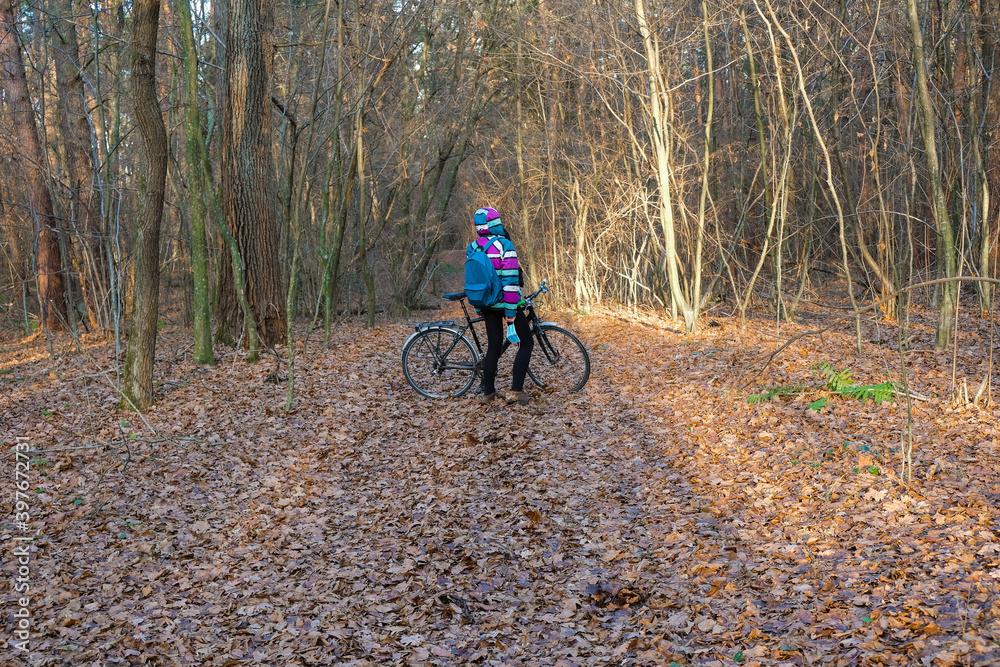 A woman in colorful clothes took off a protective mask on a bike ride in the woods. A woman enjoys solitude avoiding social contact during the coronavirus.
