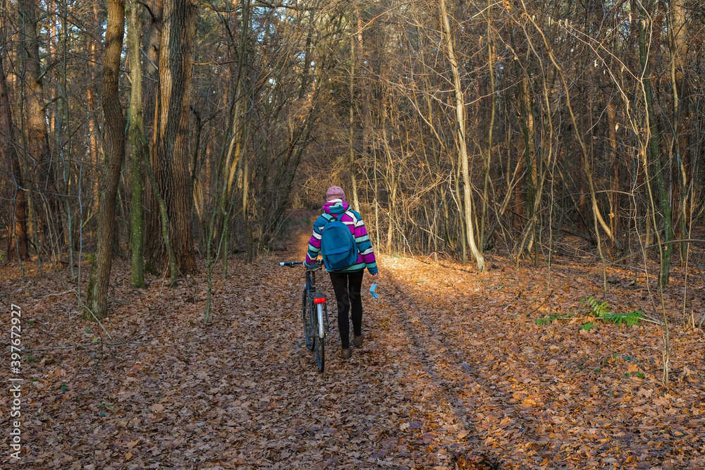A woman with a bicycle took off a protective mask in the woods. A woman enjoys solitude avoiding social contact during the coronavirus. A woman with a bicycle took off a protective mask in the woods. A woman enjoys solitude avoiding social contact during the coronavirus.