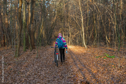 A woman with a bicycle took off a protective mask in the woods. A woman enjoys solitude avoiding social contact during the coronavirus.