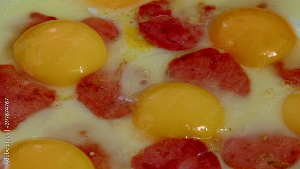 eggs with slices of sausage and melted cheese are fried in a pan in sunflower oil eggs with slices of sausage and melted cheese are fried in a pan in sunflower oil