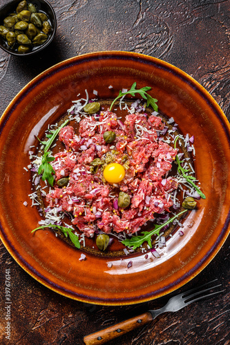French cuisine Beef tartare with raw egg yolk. Dark background. Top view