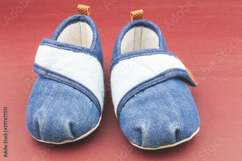 Baby shoes on red background.