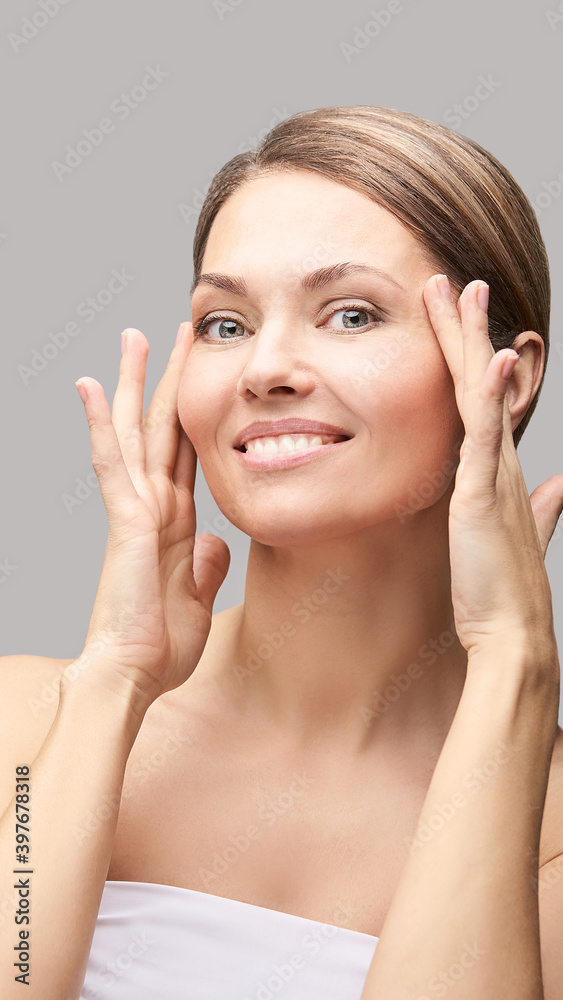 Happy pretty woman. Hands near face. Skincare concept. Home morning routine. Clean skin. Cream cosmetics. Cosmetology therapy. Rejuvenation procedure. Grey background. Copyspace