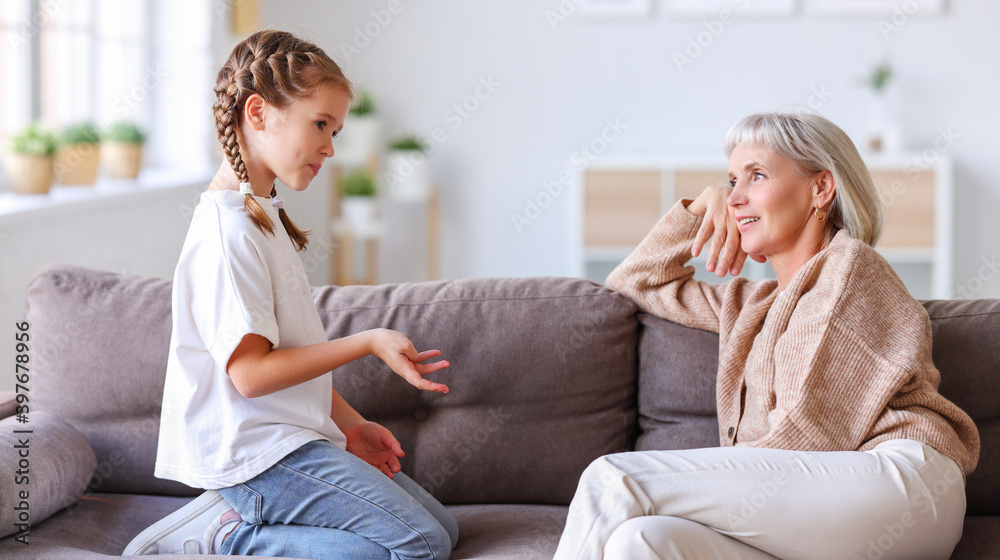 Optimistic grandmother and granddaughter chatting on sofa. Optimistic grandmother and granddaughter chatting on sofa.