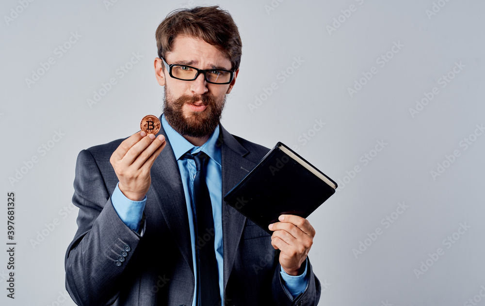 Businessman in a suit with a cryptocurrency in his hand Bitcoin coin documents currency rates Businessman in a suit with a cryptocurrency in his hand Bitcoin coin documents currency rates