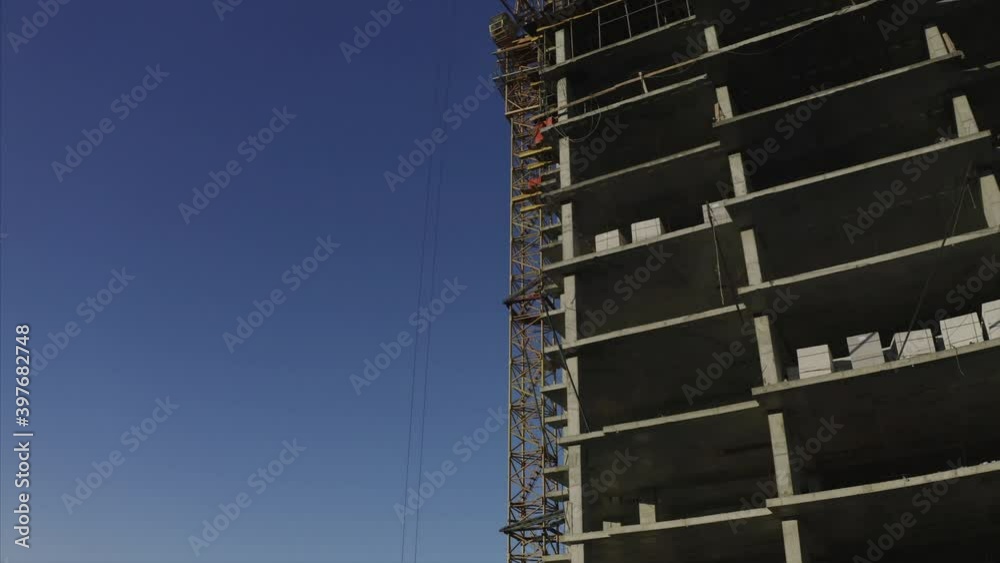 Aerial ascending view of exterios of a block of flats under construction and a crane nearby. Vladivostok, Russia Aerial ascending view of exterios of a block of flats under construction and a crane nearby. Vladivostok, Russia