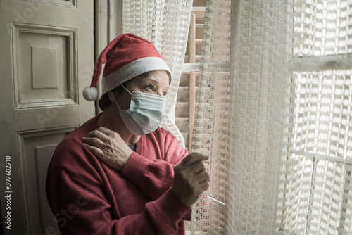 senior woman having sad Christmas alone during covid19 - mature retired lady 60s or 70s in Santa Claus hat looking depressed and emotional at home feeling lonely and melancholic © TheVisualsYouNeed