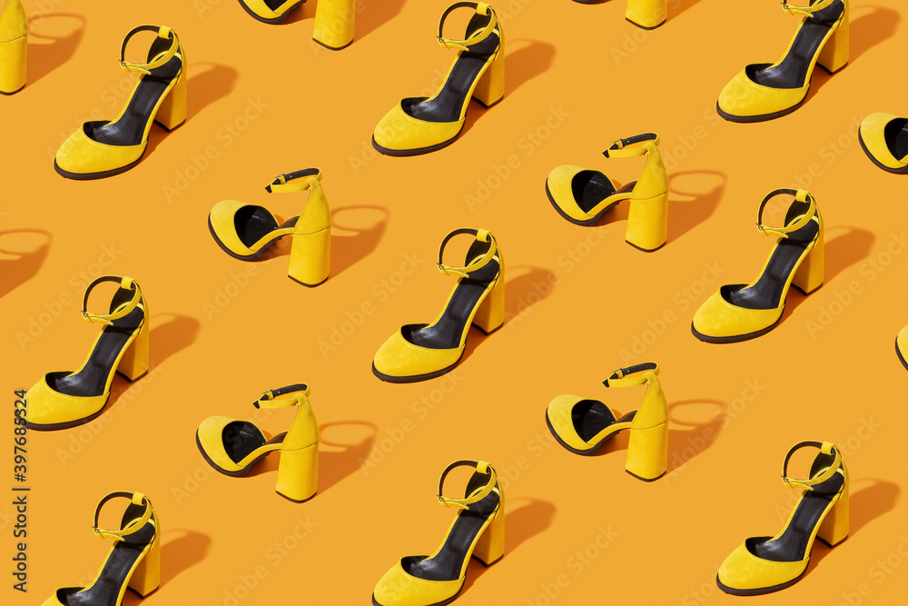 Pattern made with yellow female suede shoes on orange background. Minimal fashion concept.