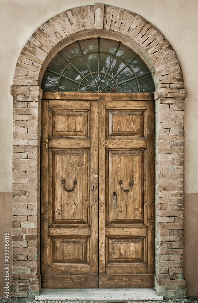 Ancient wooden door - Old-fashioned portal of an historical building with brick arch. Ancient wooden door - Old-fashioned portal of an historical building with brick arch.