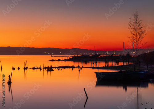 Sunset over lake, wooden pier and old fishing boat