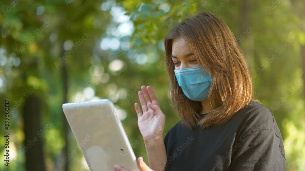 Slow Motion Infected girl in blue medical protective mask talks on tablet computer Slow Motion Infected girl in blue medical protective mask talks on tablet computer
