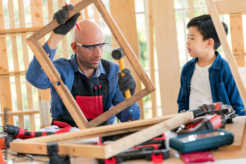 A Carpenter man teaching the boy doing carpentry work at home
