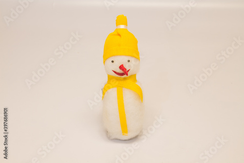 Christmas toy snowman with a red nose in a yellow hat and a scarf on a white background