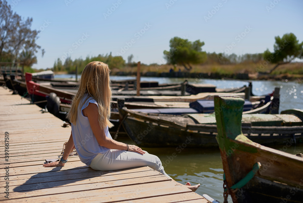 Blonde girl sitting on a jetty