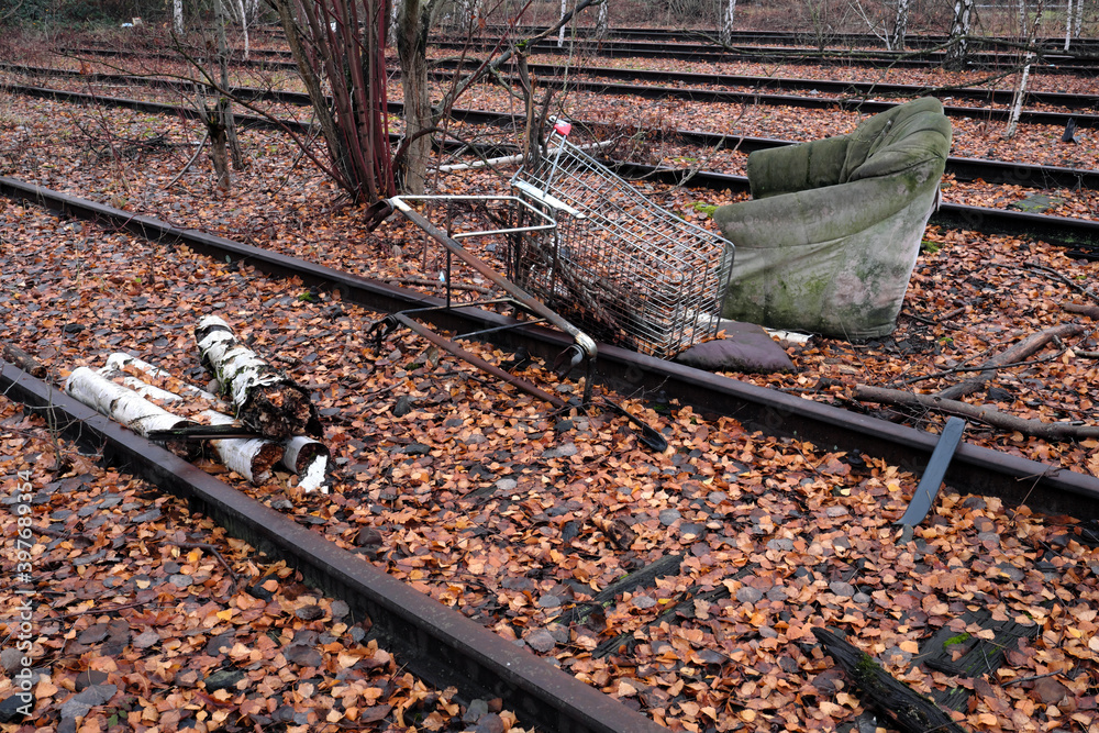 Stillgelegte Gleise in Birkenwald im Herbst und illegal entsorgter Müll mit alter Couch und Eninkaufswagen - Stockfoto Stillgelegte Gleise in Birkenwald im Herbst und illegal entsorgter Müll mit alter Couch und Eninkaufswagen - Stockfoto