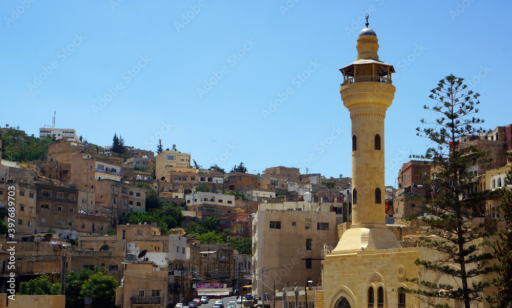 Yellow-hued minaret with the skyline of Salt in the background