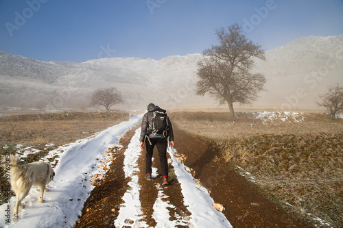 handsome man trekking with his dog in mountains in winter