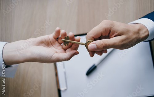 handing the key from hand to hand to the office business finance work documents