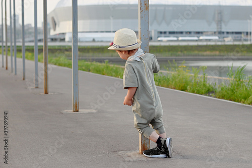 Stylish, happy child walks in the summer park by the river in a straw hat