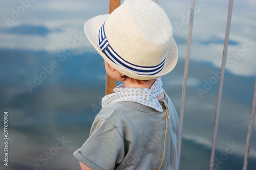 Stylish, happy child walks in the summer park by the river in a straw hat