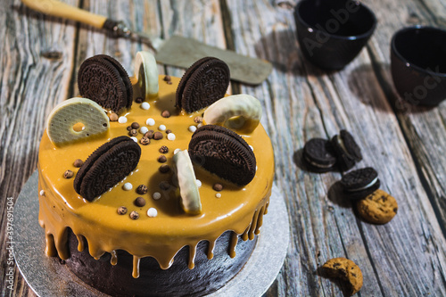 Drip chocolate cake with cookies on wood surface