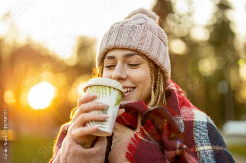 Young woman with coffee cup smiling outdoors during winter 
