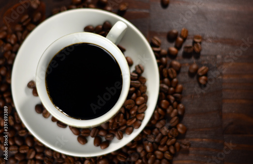 Cup of coffee and roasted coffee beans on a wooden table
