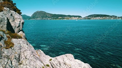 Flight over the rocky coast, clear azure water and sunny weather. The sea and mountains in the background.
 photo