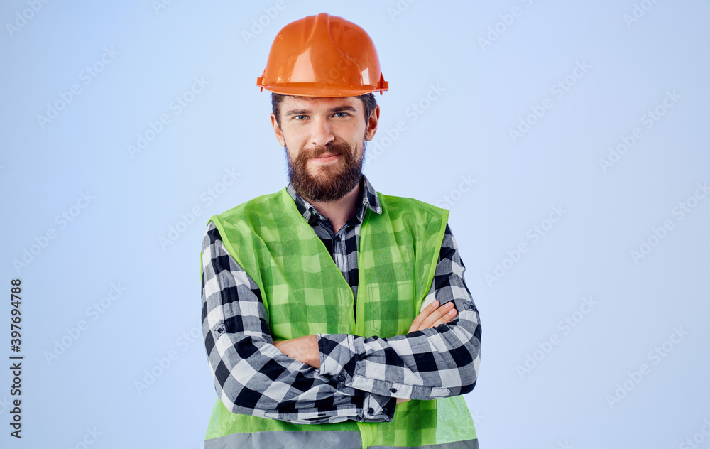 a construction worker in a helmet gestures with his hands and a reflective vest